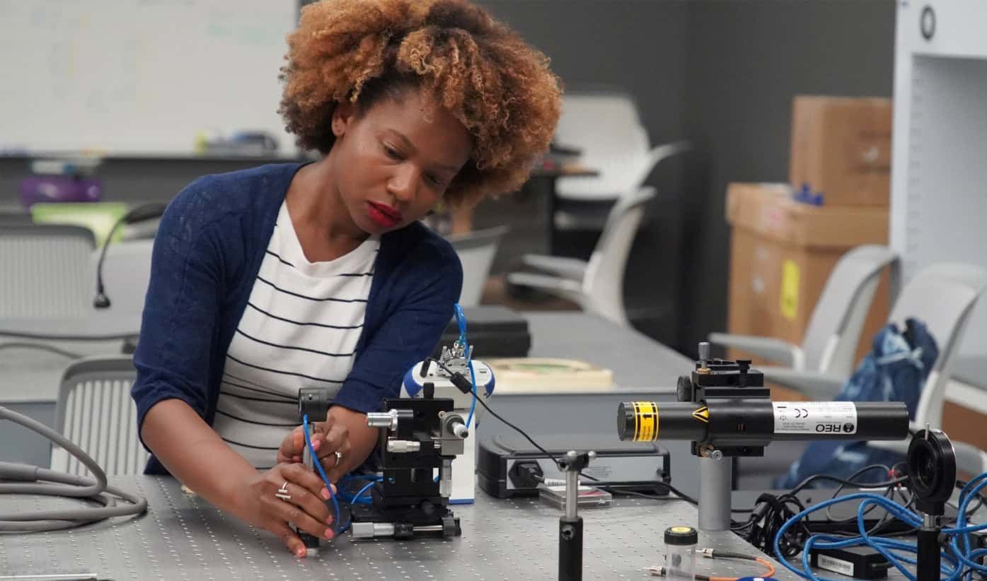 Genell adjusting components on an optical bench in a lab.